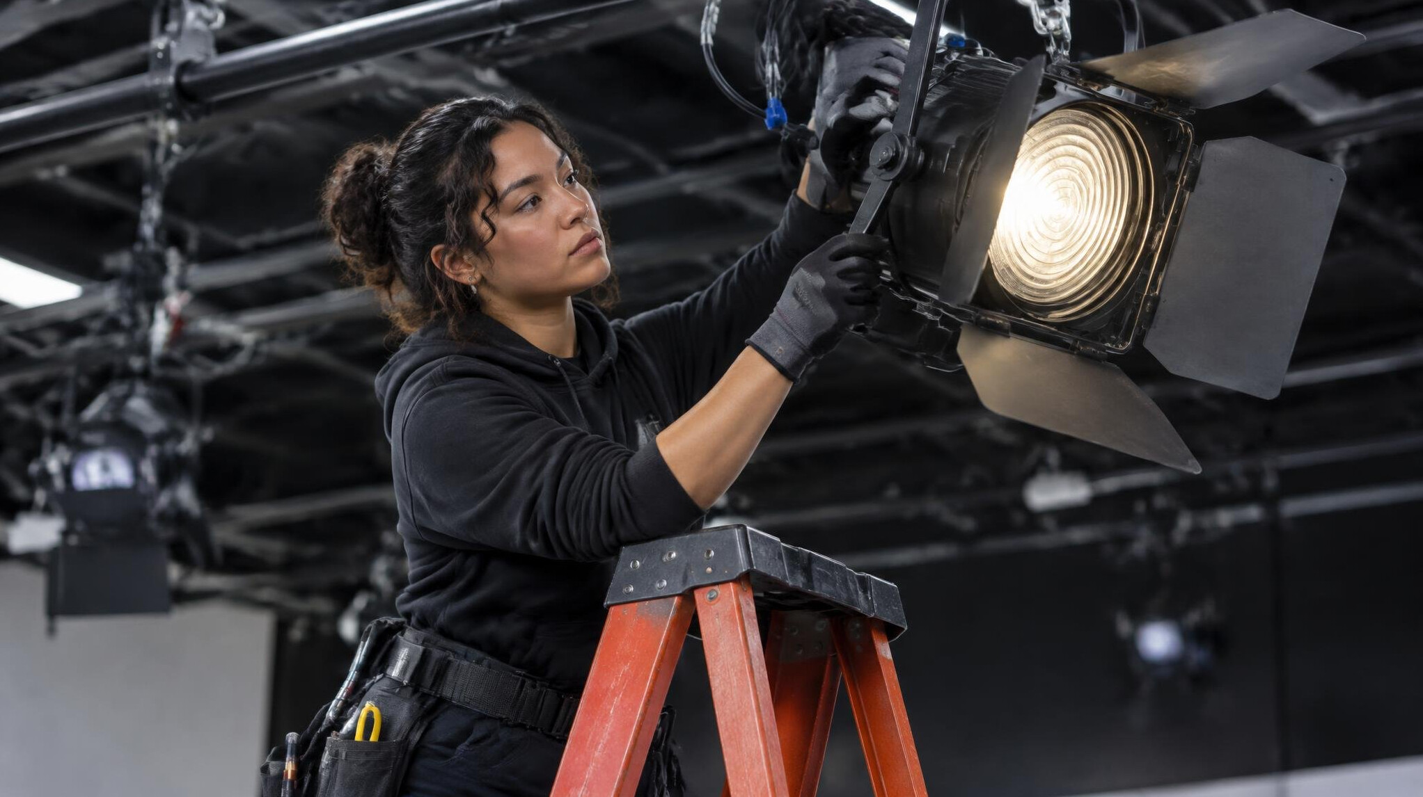 Lighting technician adjusting a fresnel light on a rig